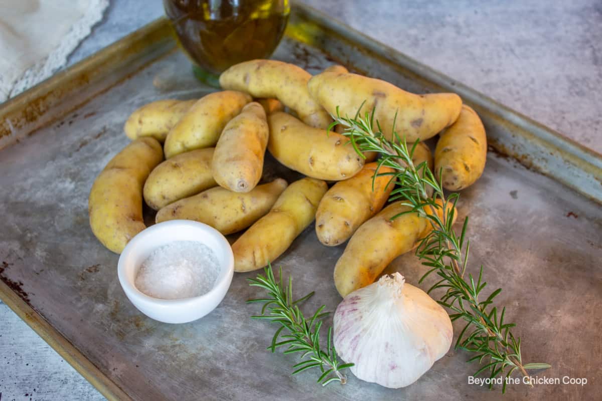 Potatoes, rosemary and garlic on a baking sheet.