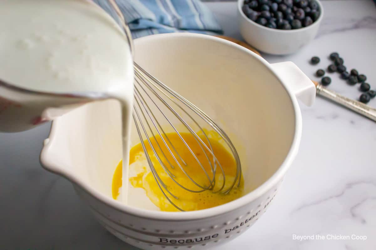 Pouring buttermilk into a bowl with a whisk. 