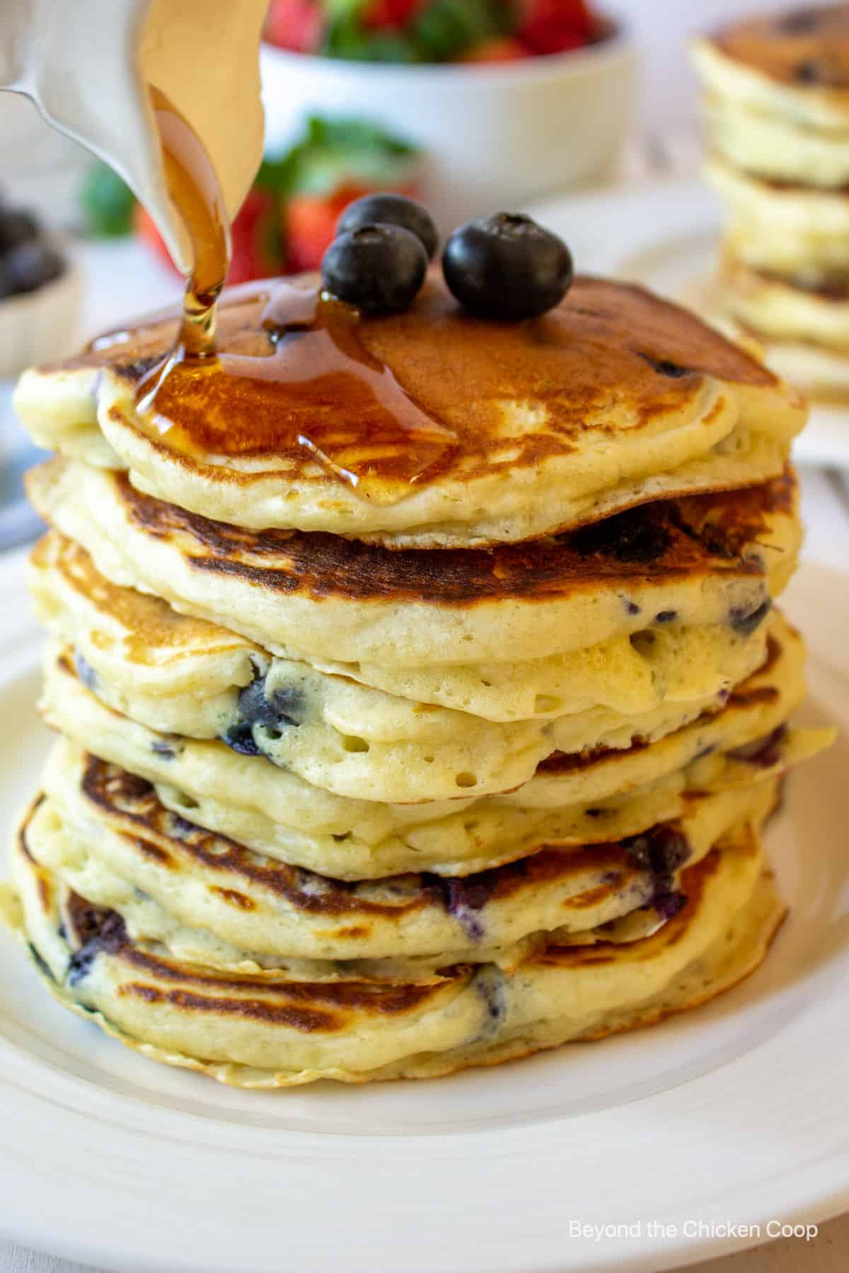 Syrup pouring over a stack of pancakes.