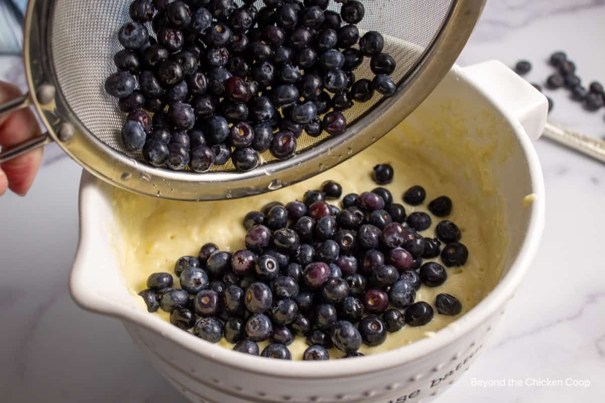 Adding blueberries to pancake batter.