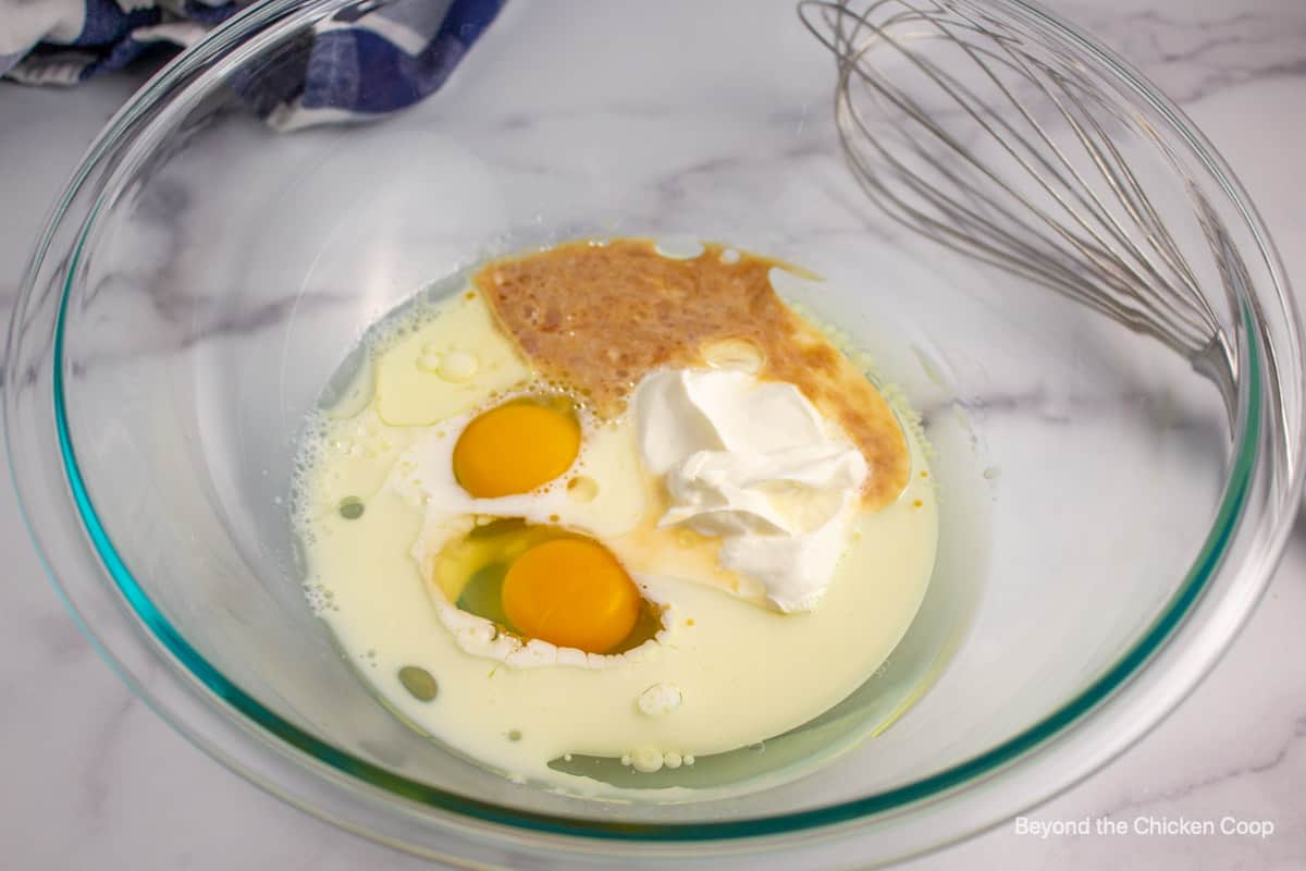 Eggs, sour cream and milk in a glass bowl.
