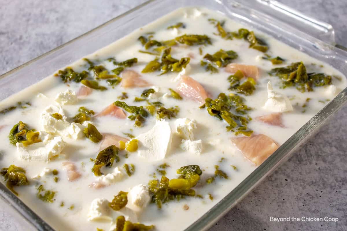 Adding chunks of chicken and green chiles to casserole.