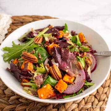 Roasted sweet potatoes, quinoa and baby greens in a bowl.