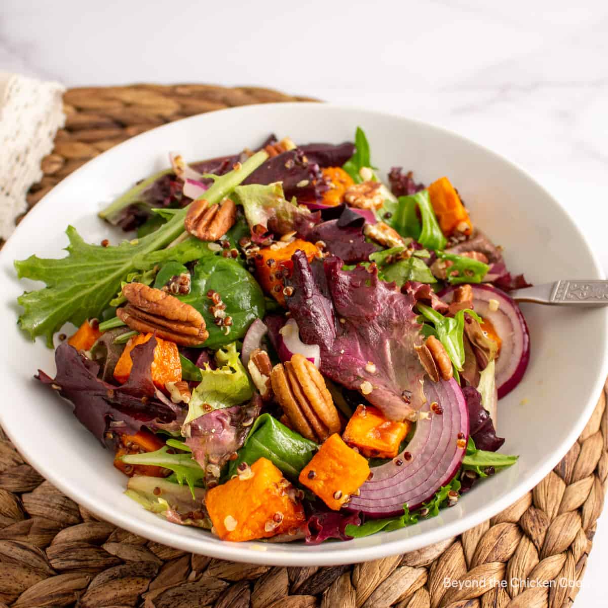 Sweet potato quinoa salad with pecans and red onions in a white bowl. 