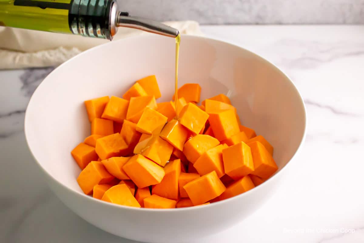 Pouring olive oil over sweet potatoes.