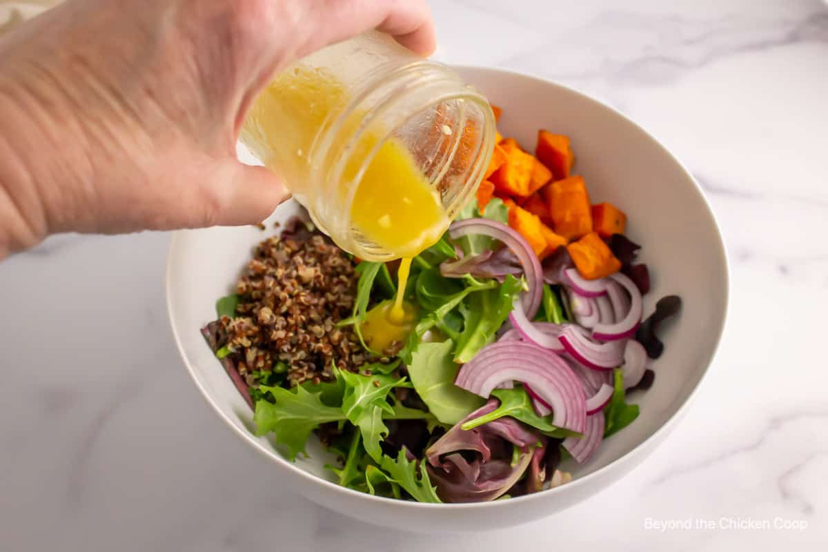 Dressing being poured over a salad.