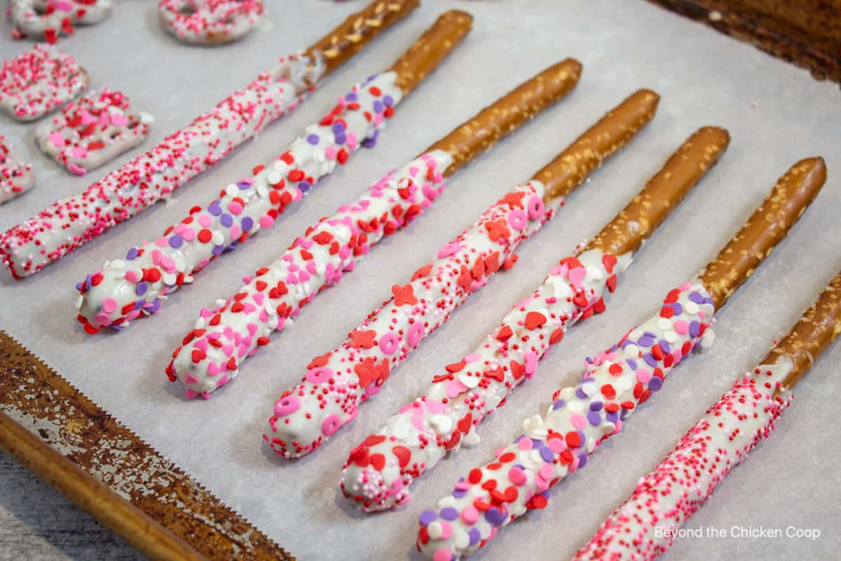 White chocolate covered pretzels covered with red and pink sprinkles. 