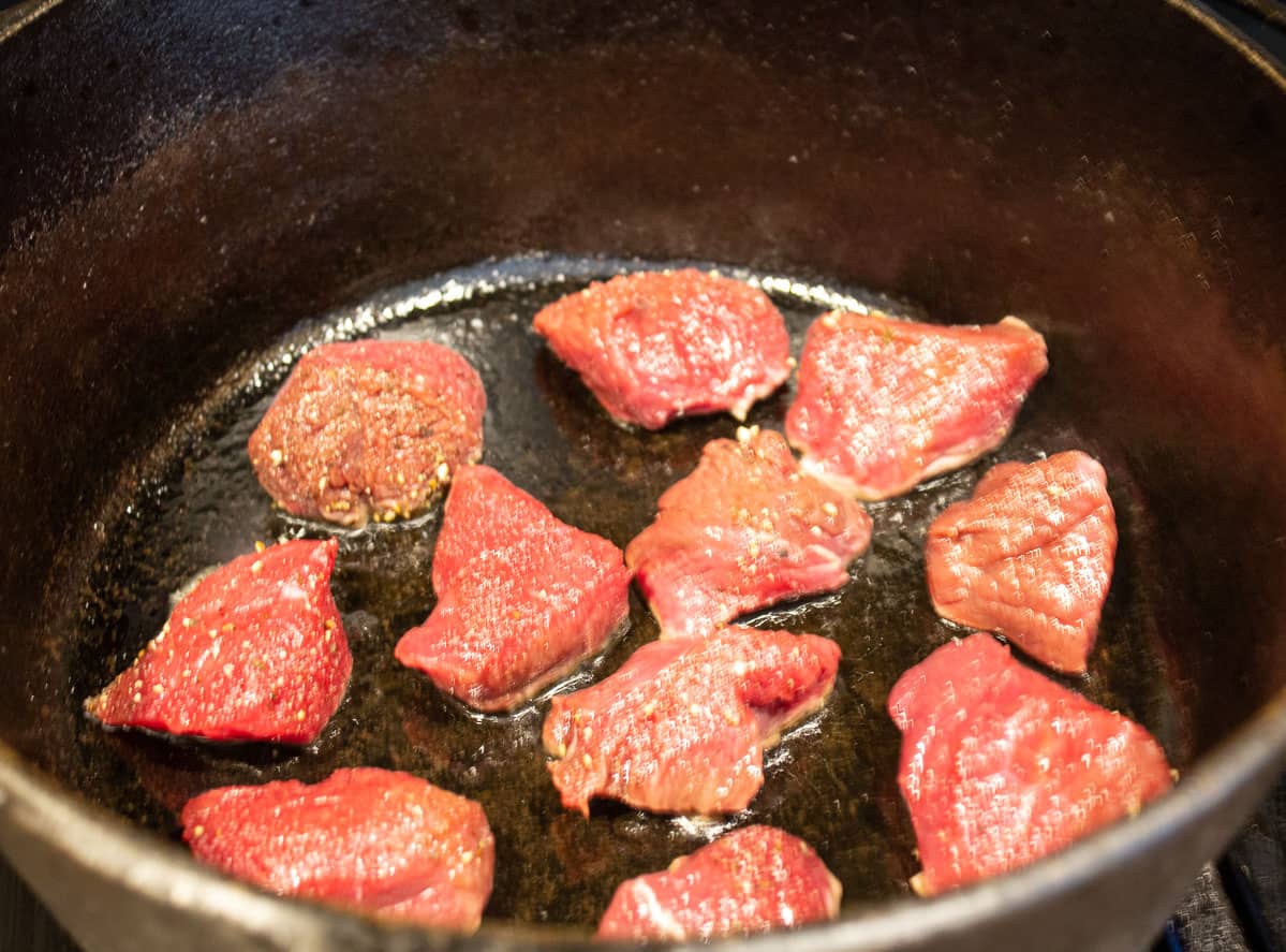 Small cubes of meat in a black pot.