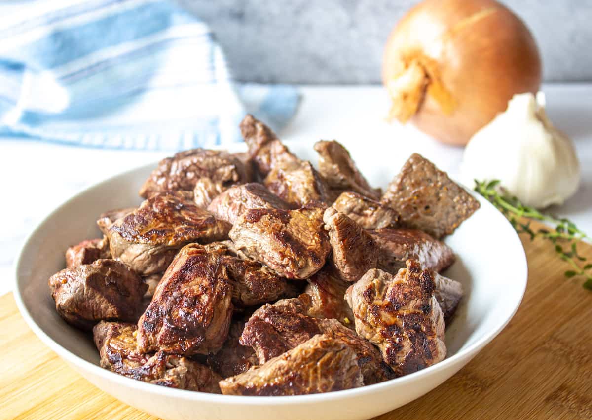 Cooked pieces of stew meat in a white bowl.