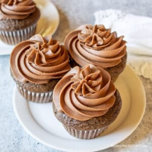 Three chocolate cupcakes with chocolate frosting.