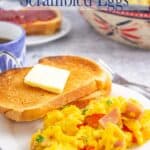 Scrambled eggs on a plate with a piece of toast.