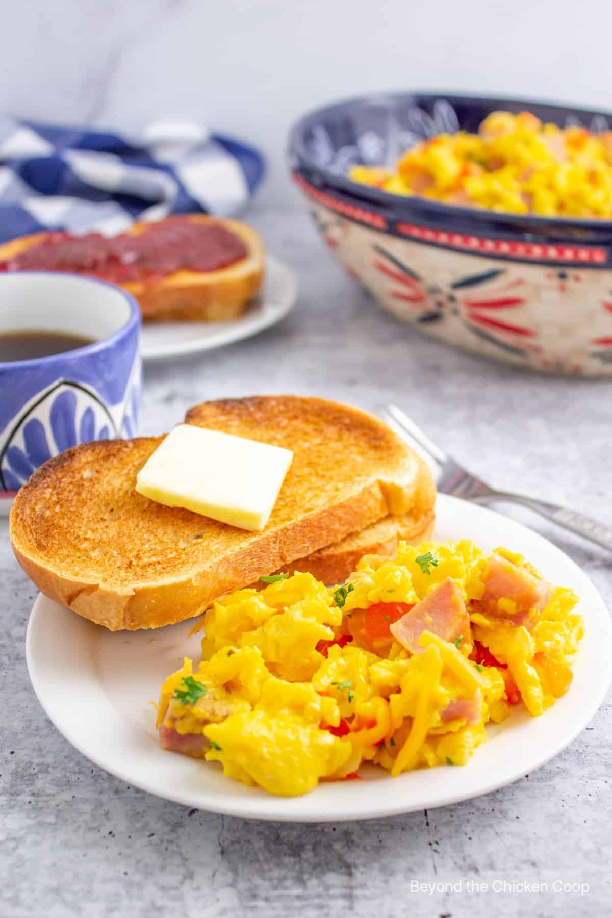 A scrambled egg breakfast with red bell peppers and ham. 
