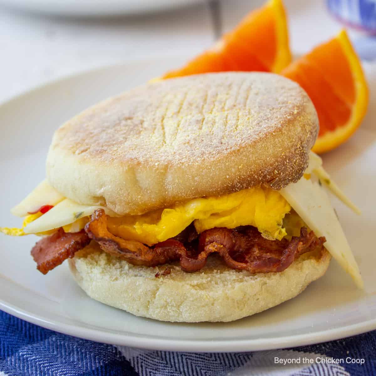 An English muffin breakfast sandwich with bacon, eggs and cheese.