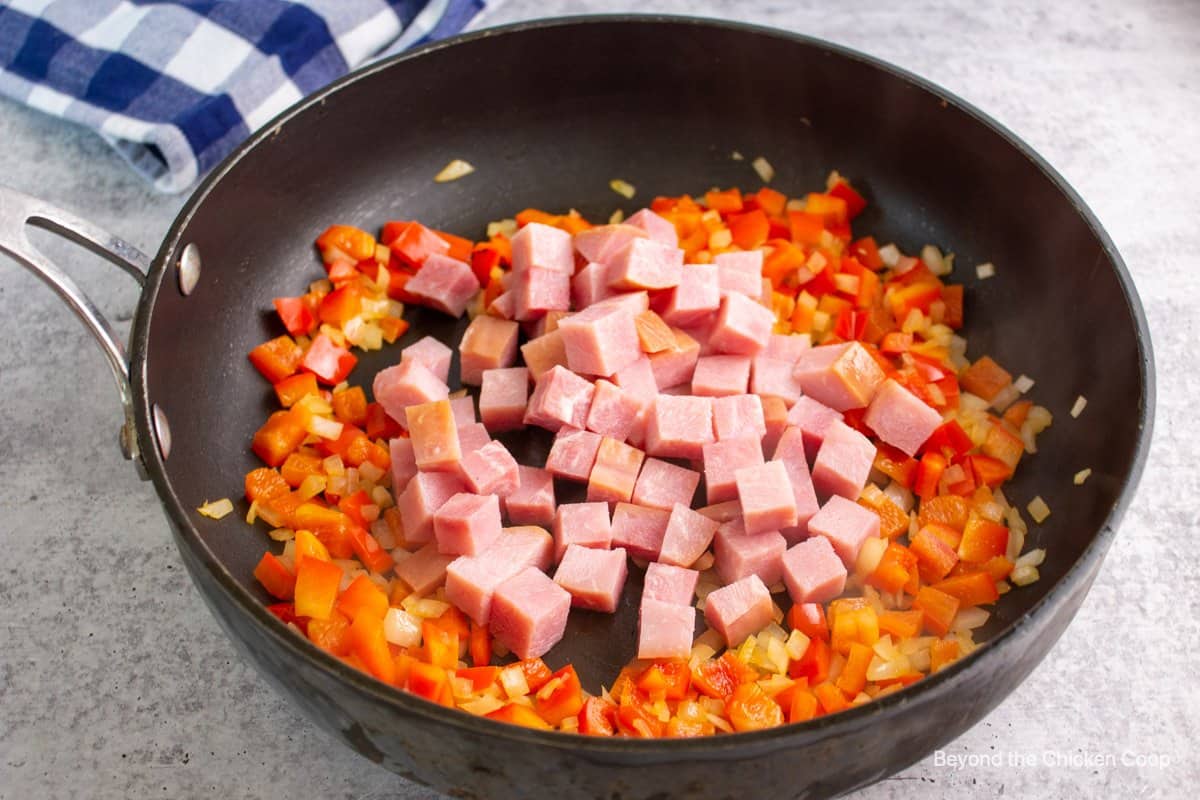 Cubed ham in a pan with peppers and onions. 