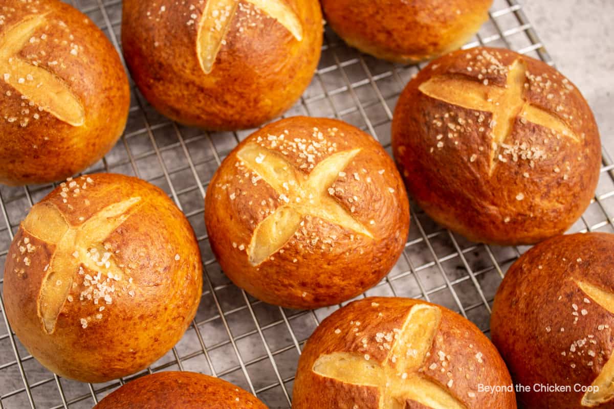 Cooked pretzel buns on a baking rack.