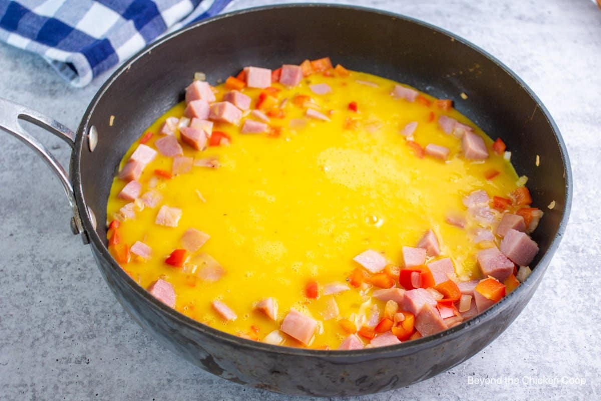 Uncooked scrambled eggs in a saute pan. 