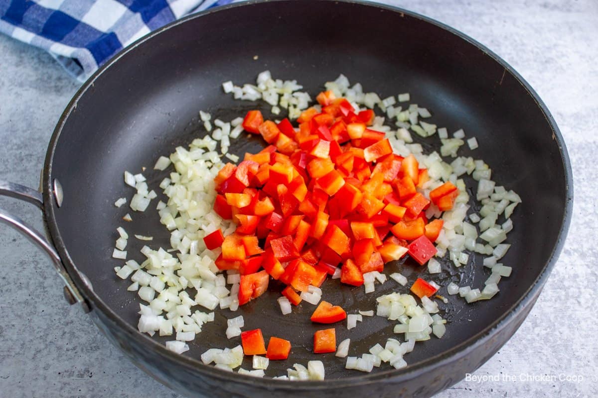 Cooking onions and red bell peppers together. 