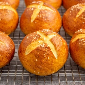 Pretzel rolls on a baking rack.