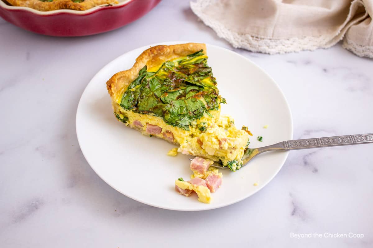 A slice of quiche with spinach.