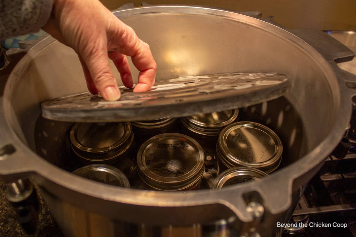 Placing a divider over canning jars in a pressure cooker.