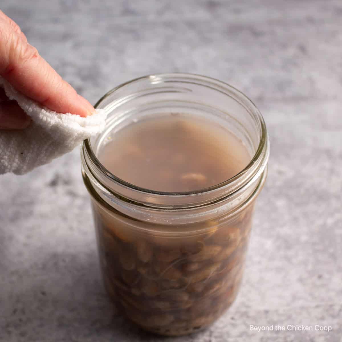 Wiping the rim of a canning jar.