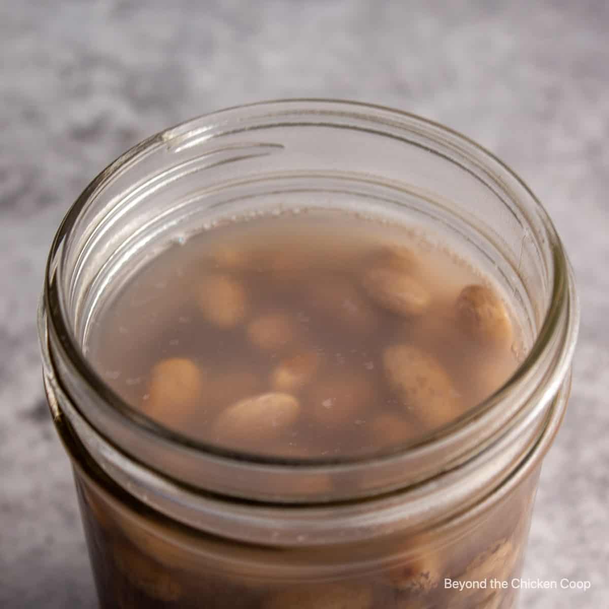 Cooking liquid over beans in a jar.