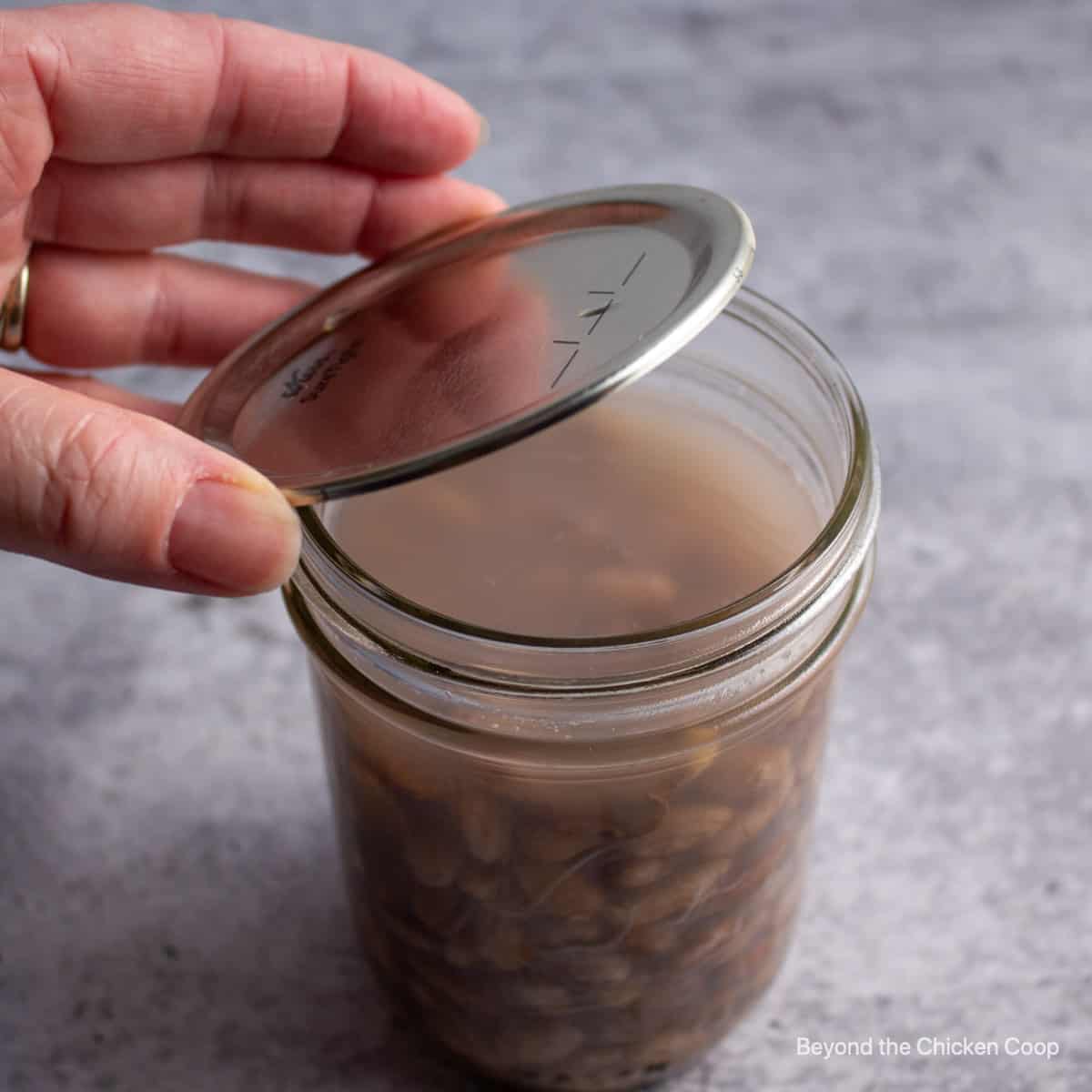 Adding a lid to a canning jar of beans.
