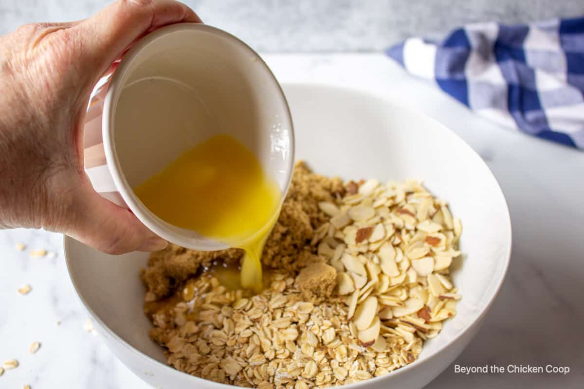 Pouring melted butter over oats.