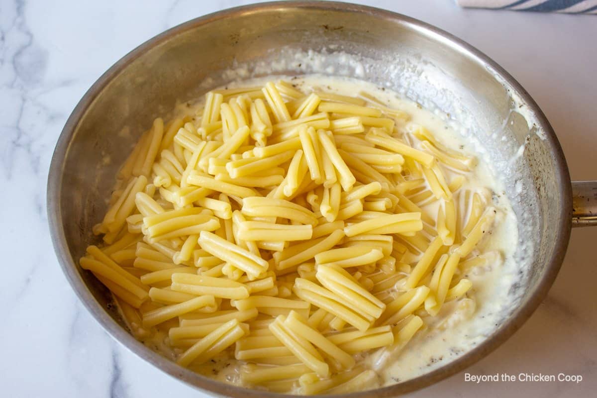 Pasta in a pan with heavy cream.