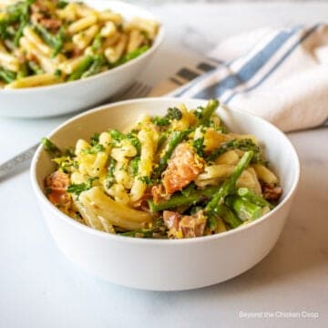 A bowl of pasta with salmon and asparagus.