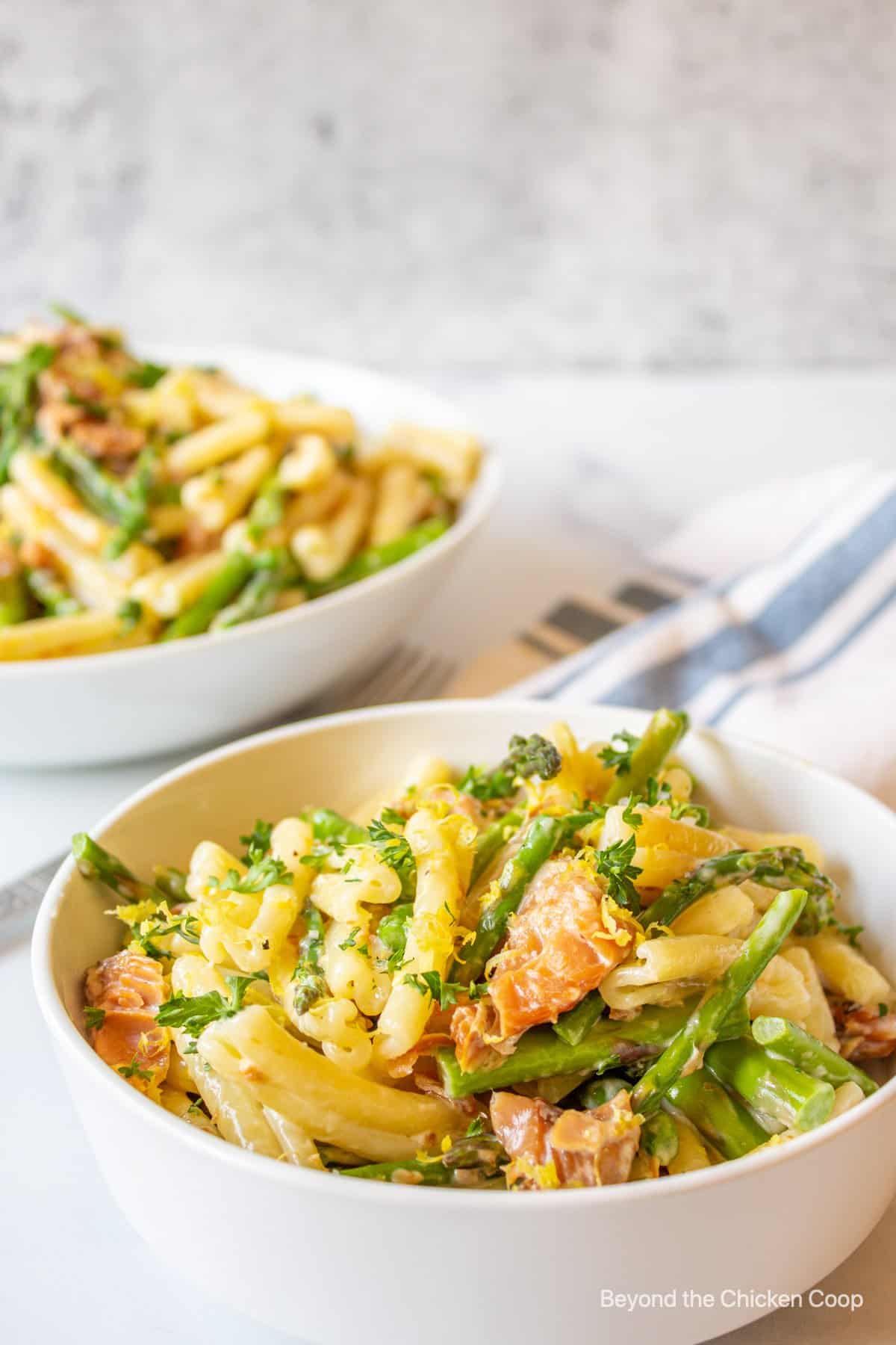 A bowl of pasta with fish and asparagus.