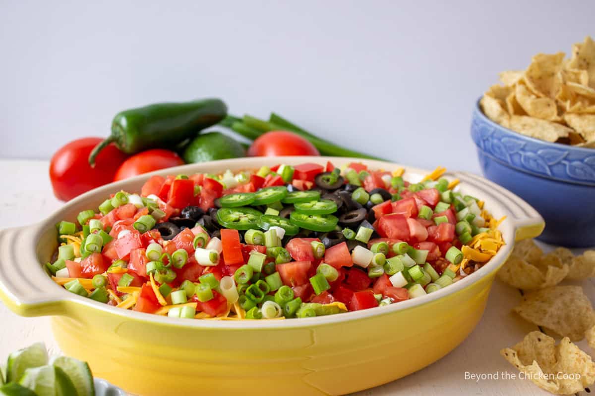 A layered bean dip in a yellow dish.