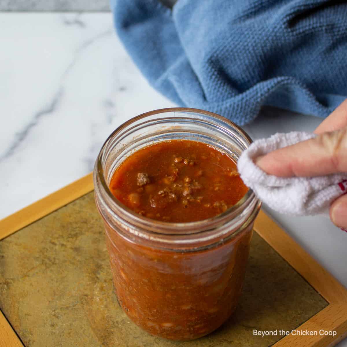 Wiping down rim of canning jar.