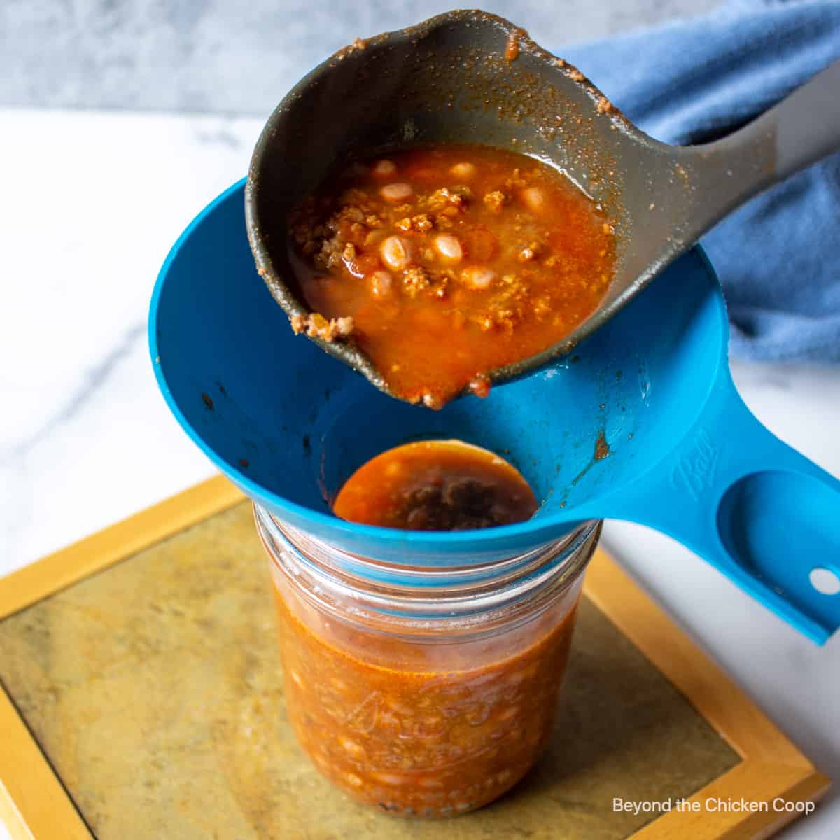 Ladeling chili into canning jars.