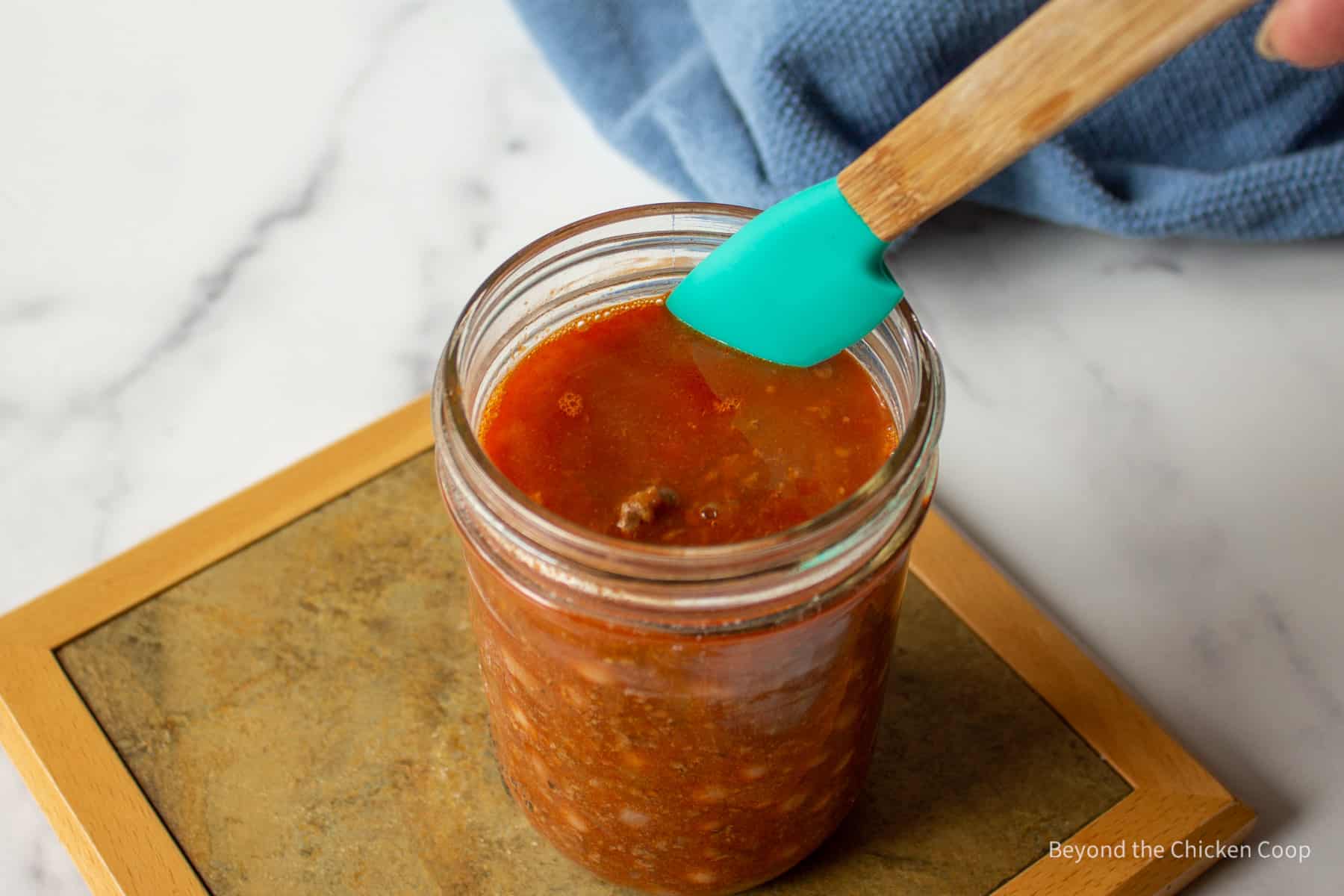 Removing air bubbles from a jar of chili.