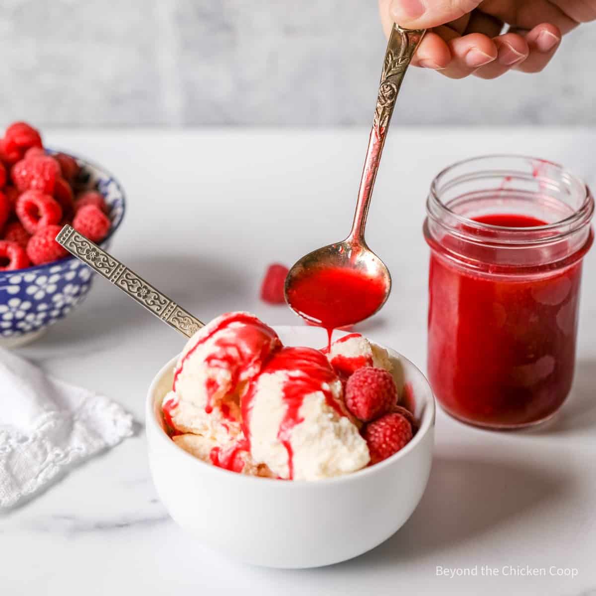 Raspberry sauce being ladled over ice cream.