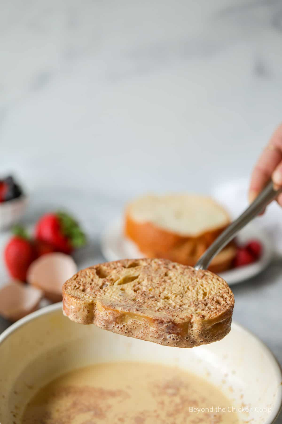 Removing the bread from the custard mixture.