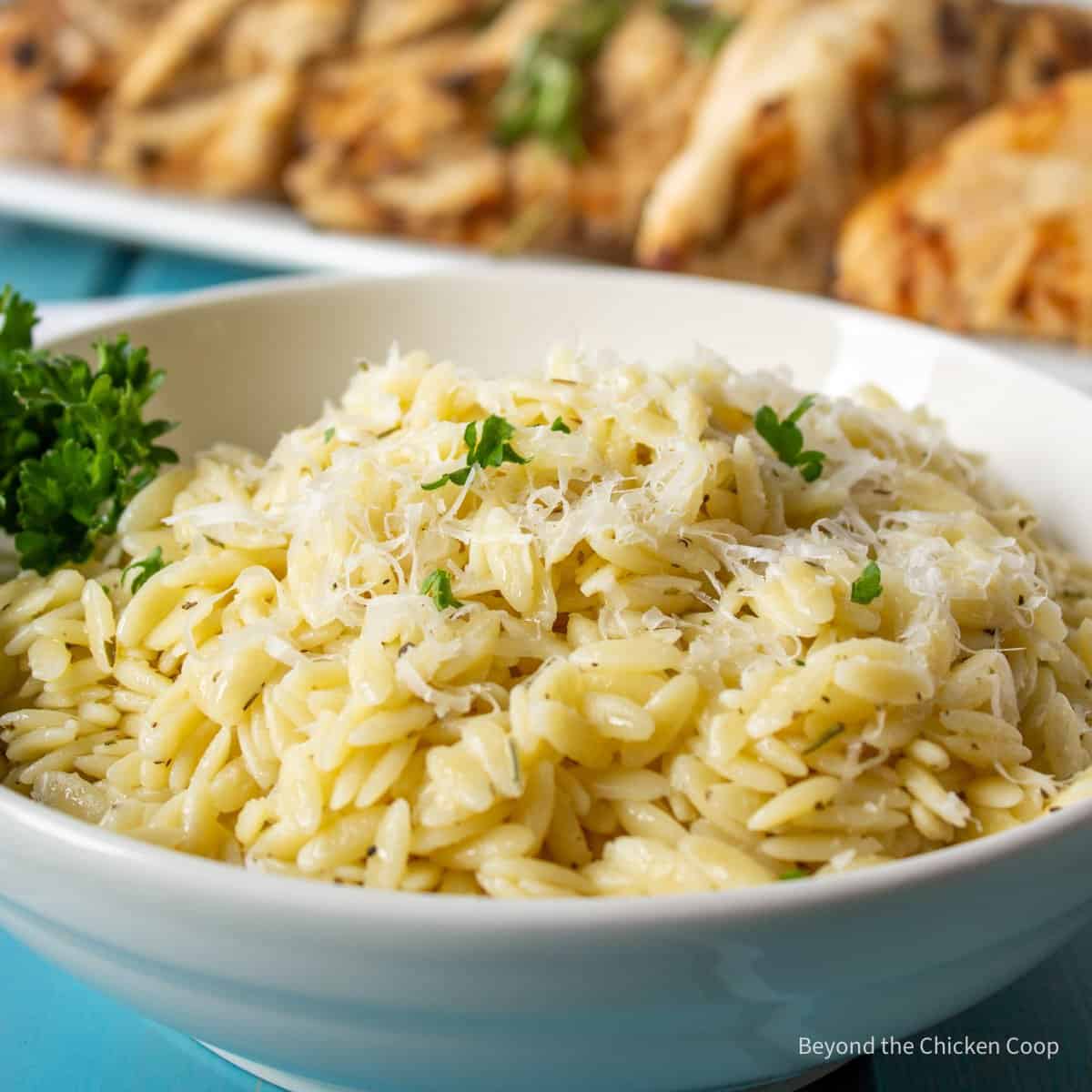 A dish filled with orzo topped with cheese.