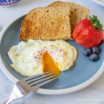 A fried egg with the yolk spilling out of the center of the egg.