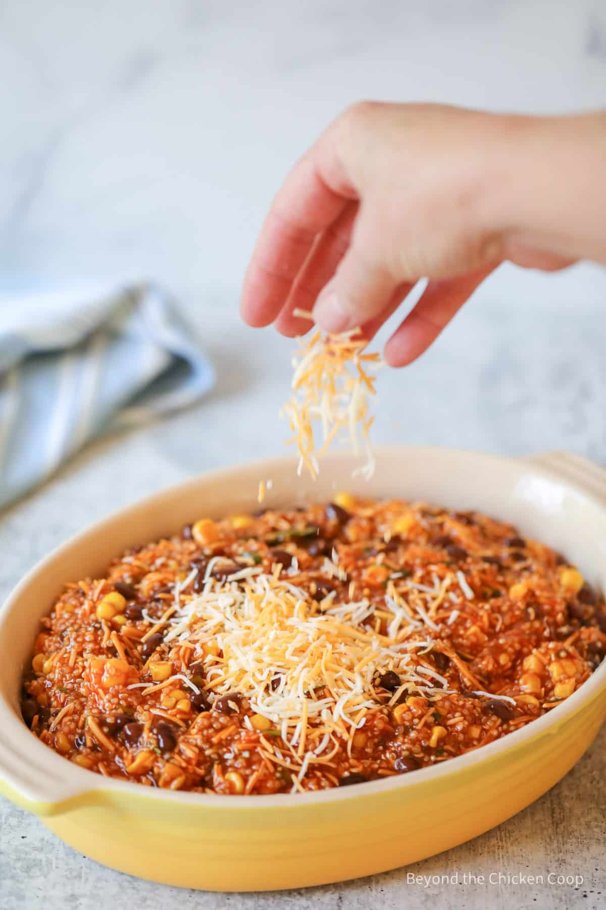 Sprinkling cheese over a casserole dish.