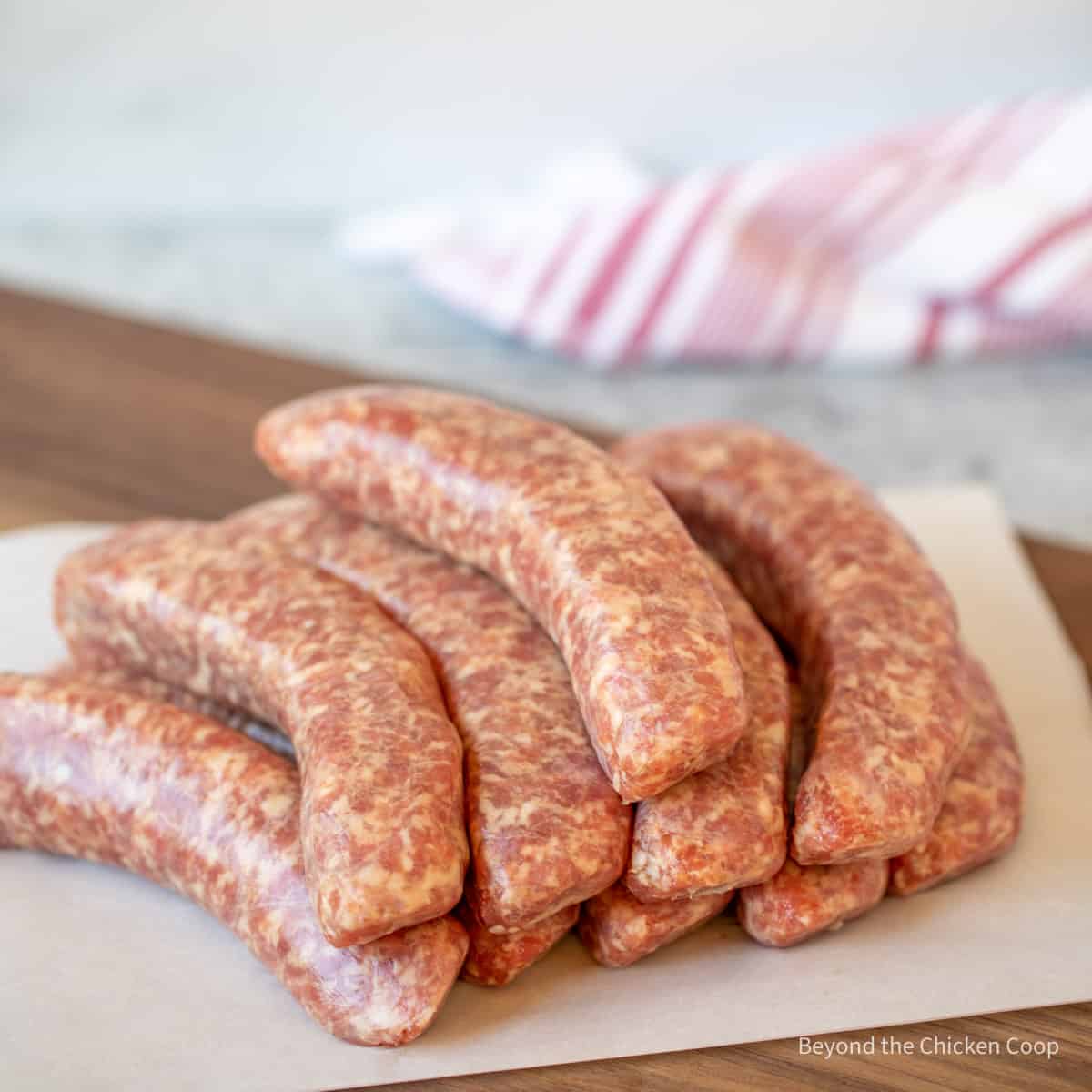 A pile of uncooked bratwurst on a wooden board.