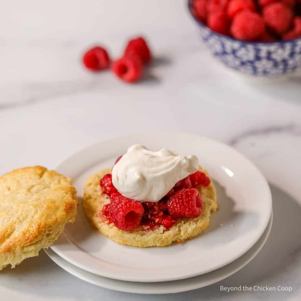 A dollop of whipped cream on top of raspberries.