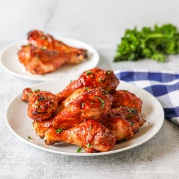 A plate filled with chicken legs covered in barbecue sauce.