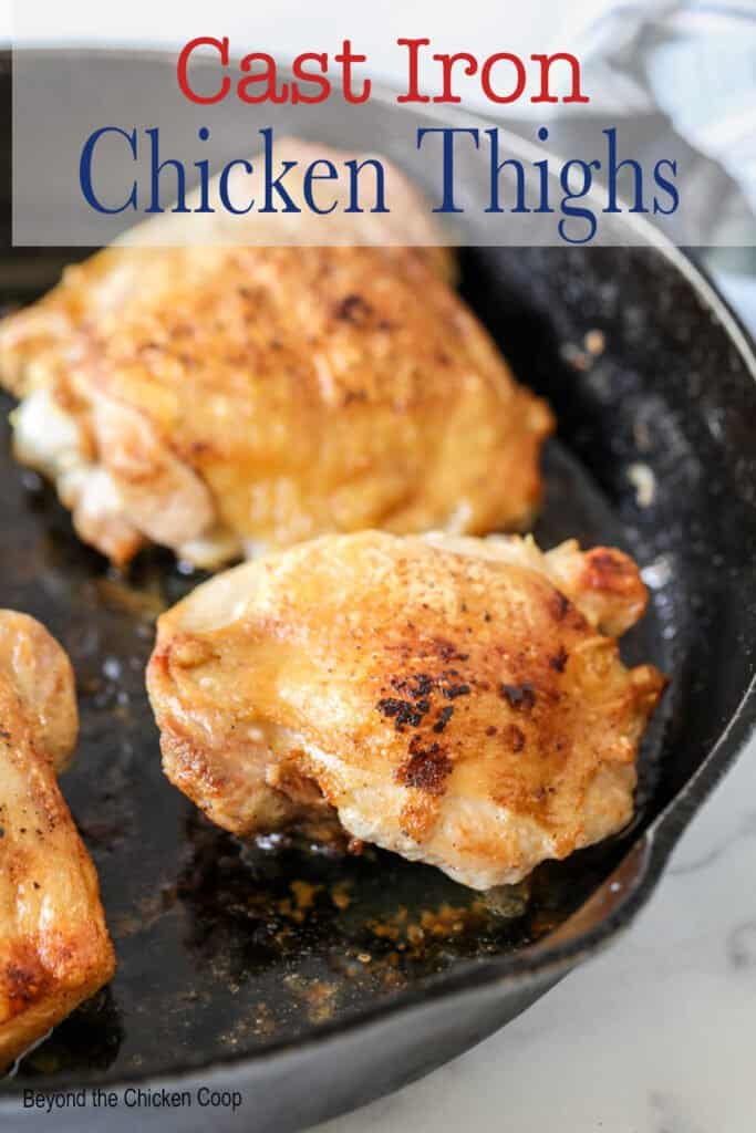 A cast iron skillet with cooked chicken thighs.
