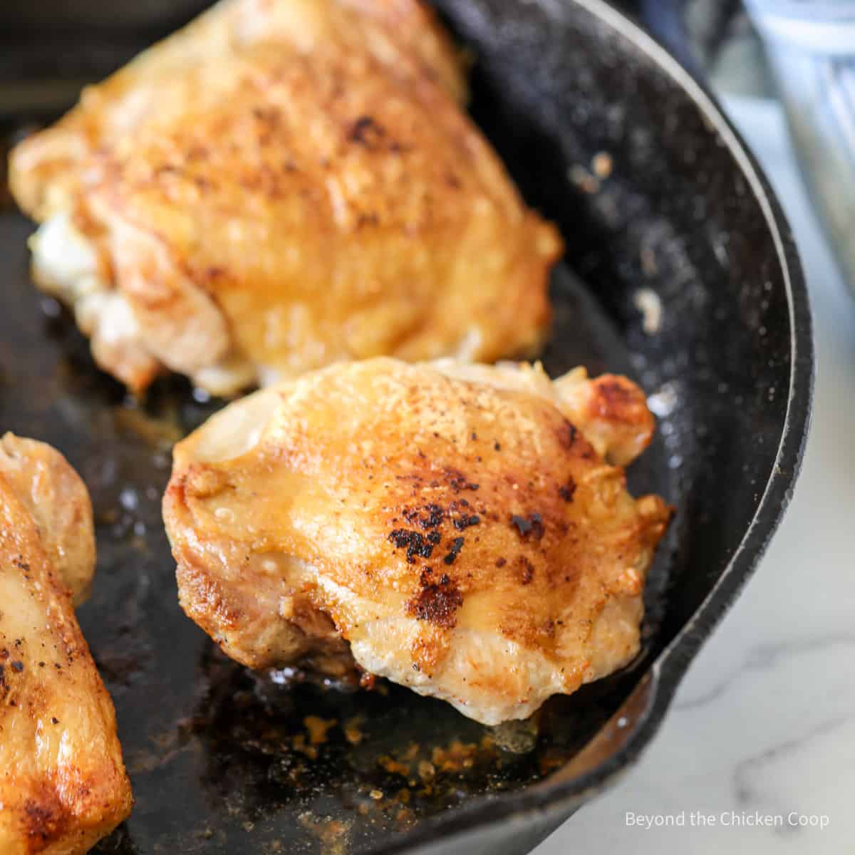 Chicken thighs in a cast iron skillet.