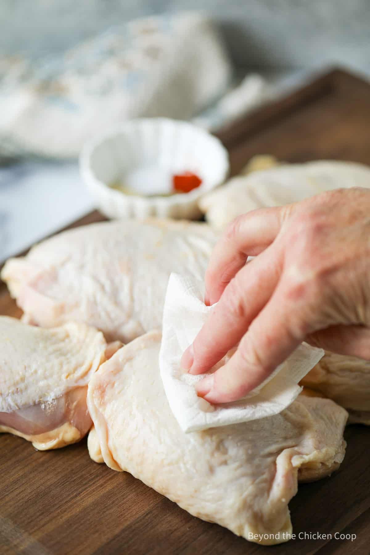 Patting chicken thighs with a paper towel.