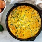 A frittata with zucchini in a cast iron skillet.