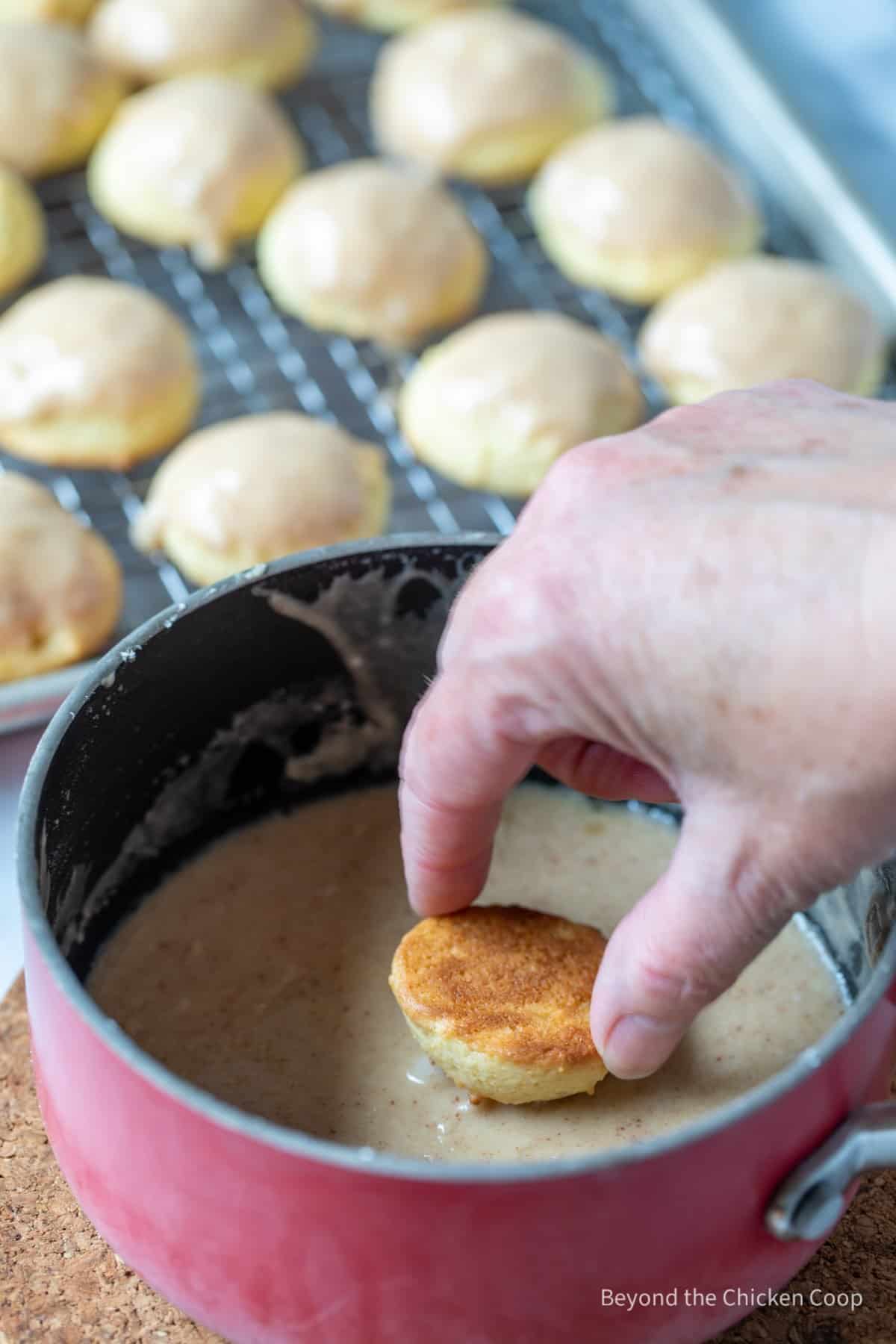 Dipping a cookie into a glaze.