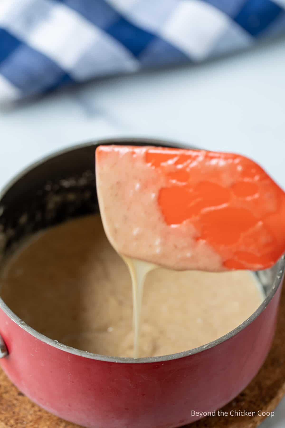 Brown butter frosting dripping off a spatula.