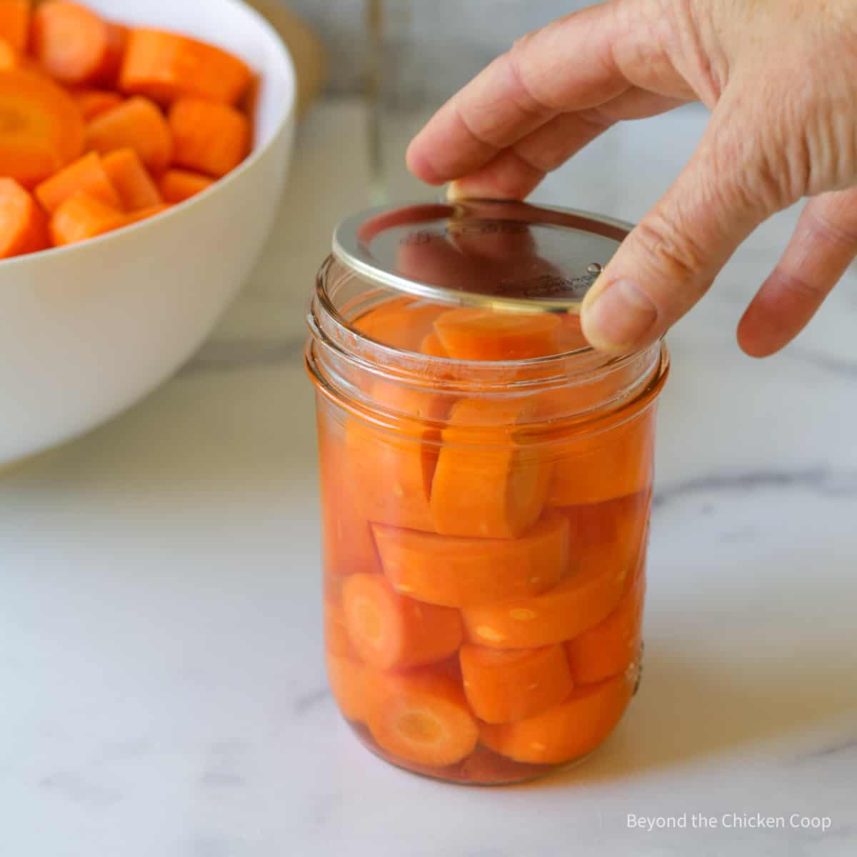 Adding a lid to a canning jar.